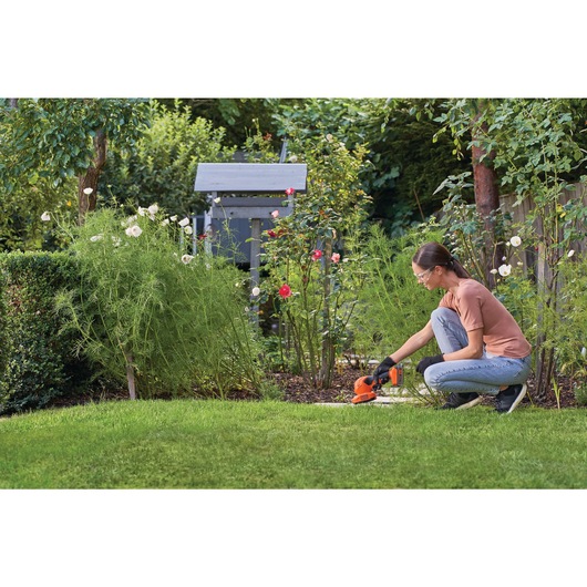 20 volt MAX shear shrubber being used by a person to shear shrubs outdoors.