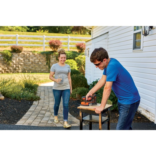 MOUSE Cordless Sander being used by person to sand wooden stool.