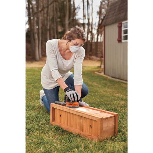 20 volt MAX cordless random orbital sander being used by a person to sand wooden drawer.