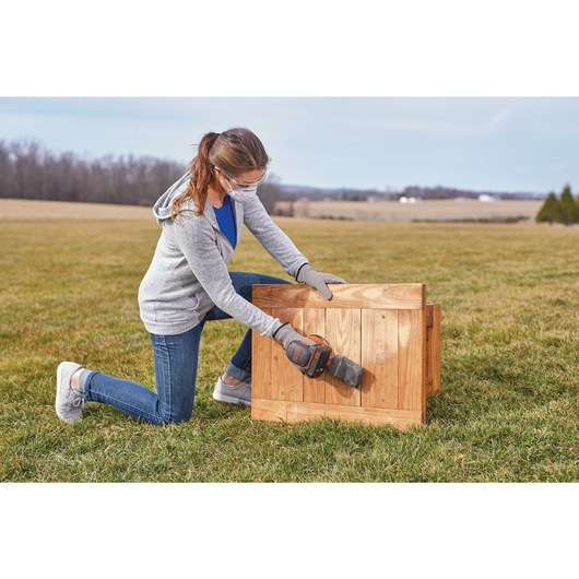20 volt MAX cordless random orbital sander being used by a person to sand wooden surface.
