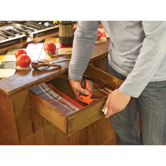 Lithium rechargeable screwdriver being used to attach a knob to a shelf.