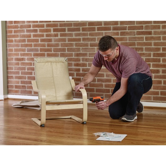 4 volt max roto bit storage screwdriver being used to screw a hole into a chair by a person.
