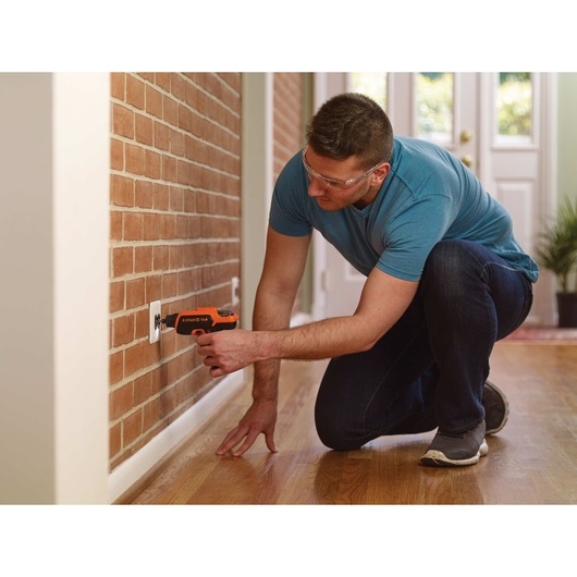 4 volt MAX ROTO BIT Storage Screwdriver being used to drill nails on a wall by a person.