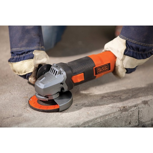 4 and half inch 6.5 Amp angle grinder being used by a person to grind hard surface.