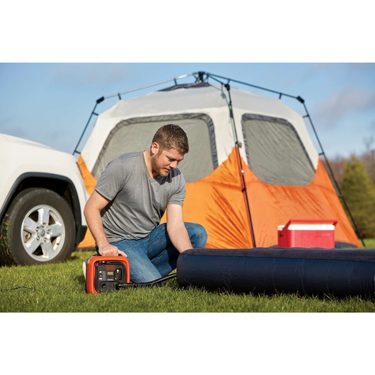 12 volt DC multi purpose inflator being used by a person to inflate air mattress.