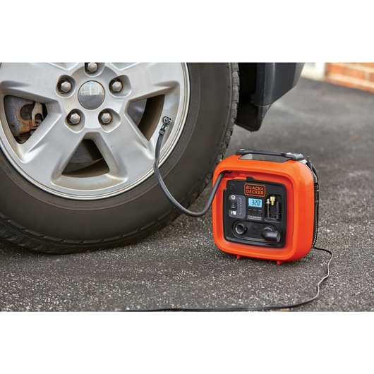 12 volt D C multi purpose inflator being used to inflate car tire.