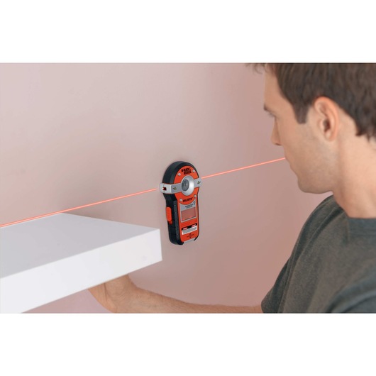 Bullseye auto leveling laser with stud sensor being used by a person for precise measurements.