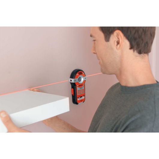 BullsEye auto leveling laser with stud sensor being used by a person for precise measurement.
