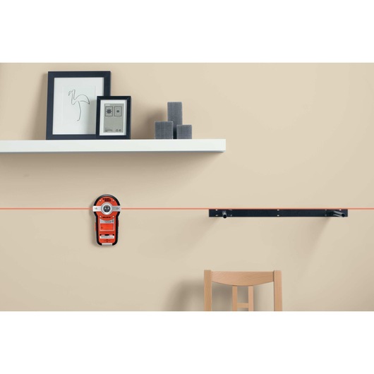 Bullseye auto leveling laser with stud sensor being used to measure a wall.