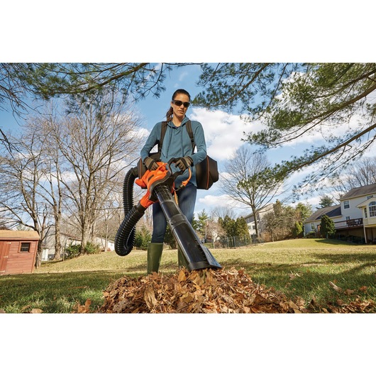 3 in 1 VAC PACK 12 Amp Leaf Blower Vacuum and Mulcher being used by person to clear dried leaves outdoors.