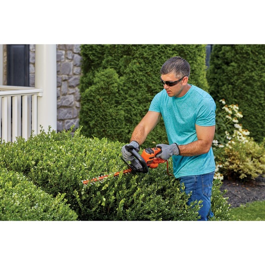 16 inch electric hedge trimmer being used by a person to trim hedges.