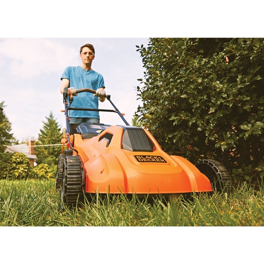 13 ampere 20 inch corded electric lawn mower being used to mow lawn.