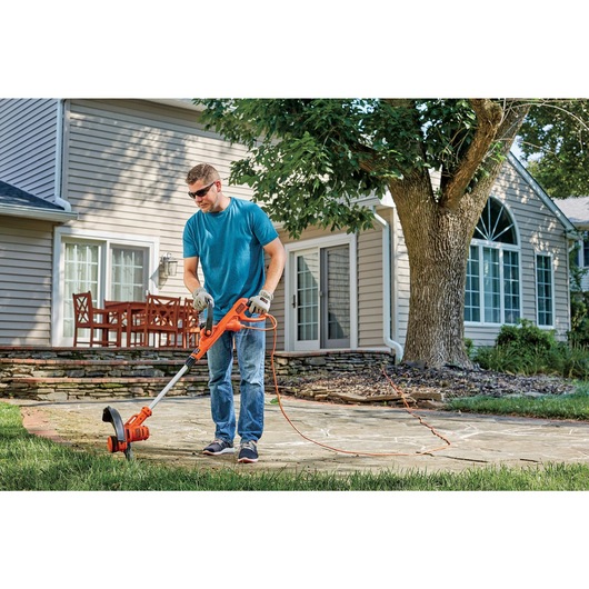 6.5 ampere 14 inch A F S electric string trimmer/edger being used to cut grass.