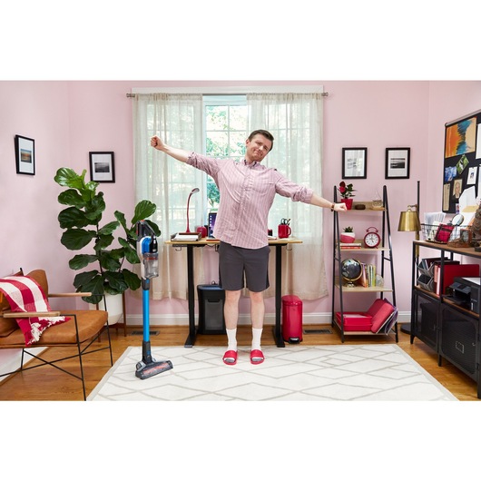 man stretching with BLACK+DECKER PowerseriesExtreme stick vacuum next to him
