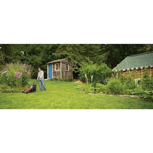 MAX Lithium 16 inch Mower being used by person to mow lush green lawns outdoors.