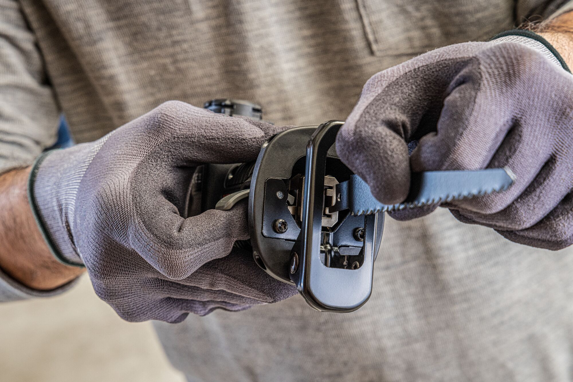 Person lifts the bland clamp release lever on the BLACK+DECKER MATRIX reciprocating saw attachment to remove a blade