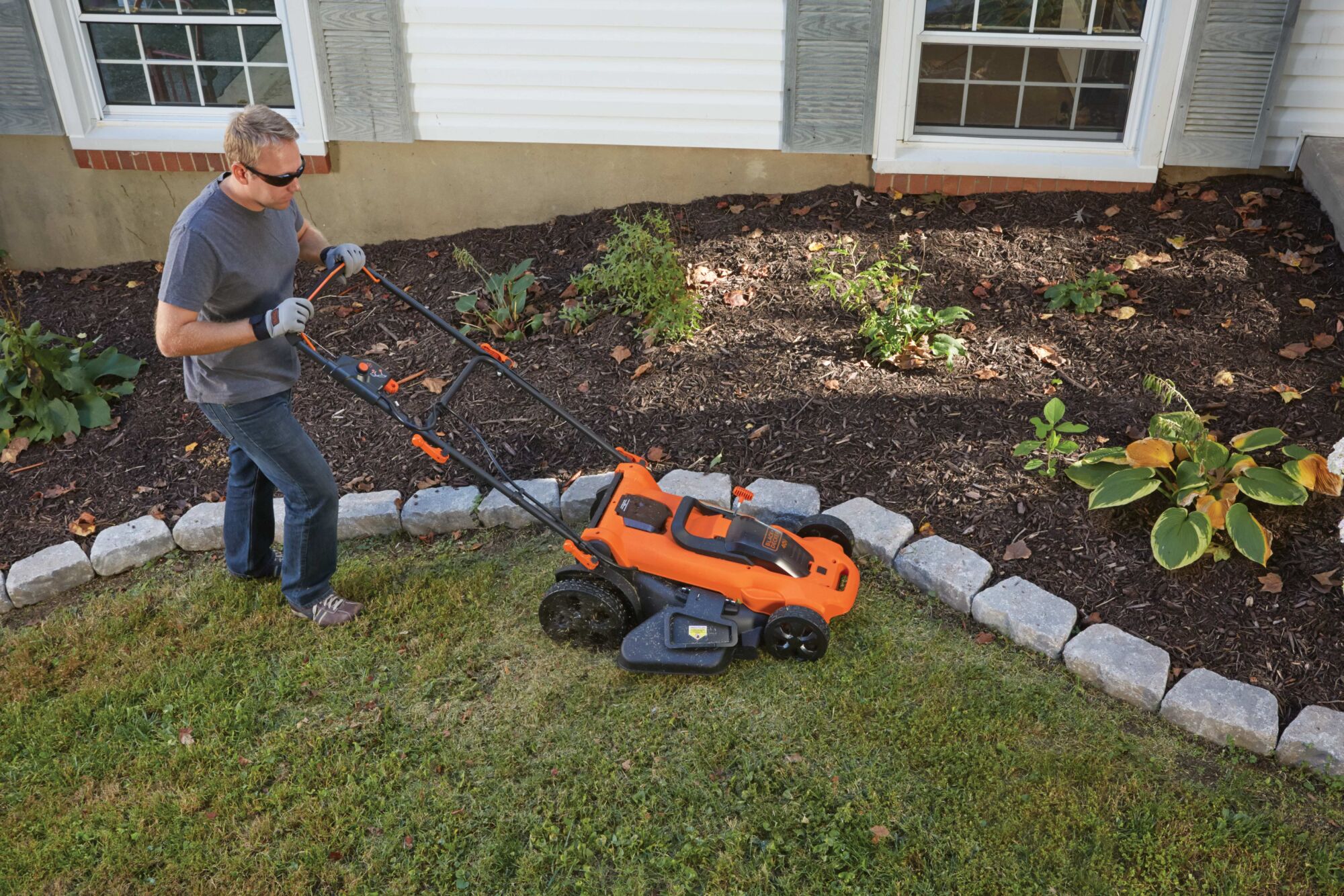 20 inch 40 volt max cordless lawn mower being used mow grass by a person in a garden.
