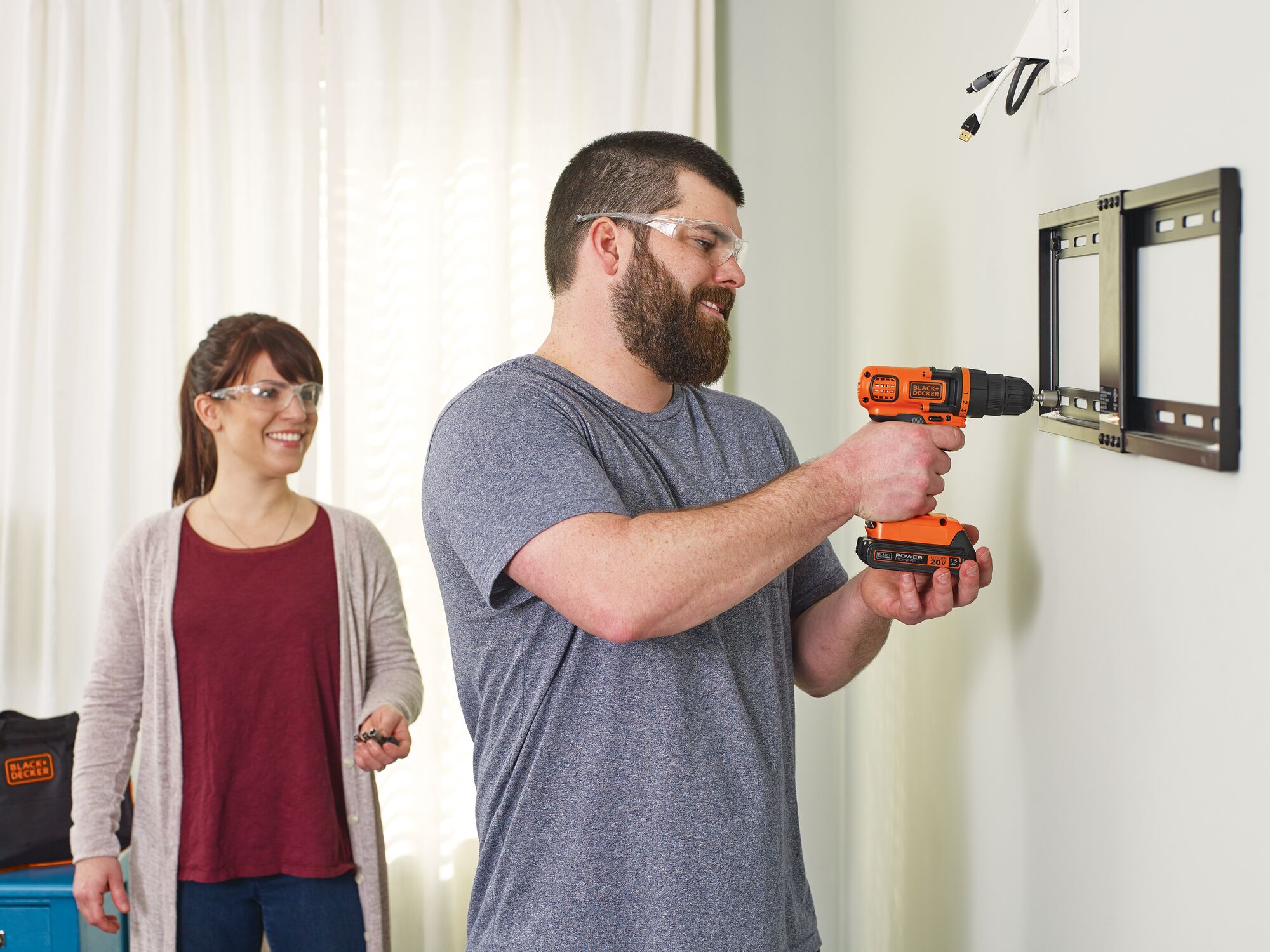 Lithium ion drill and driver plus 68 piece project kit being used to drill a tv frame into the wall by a person.