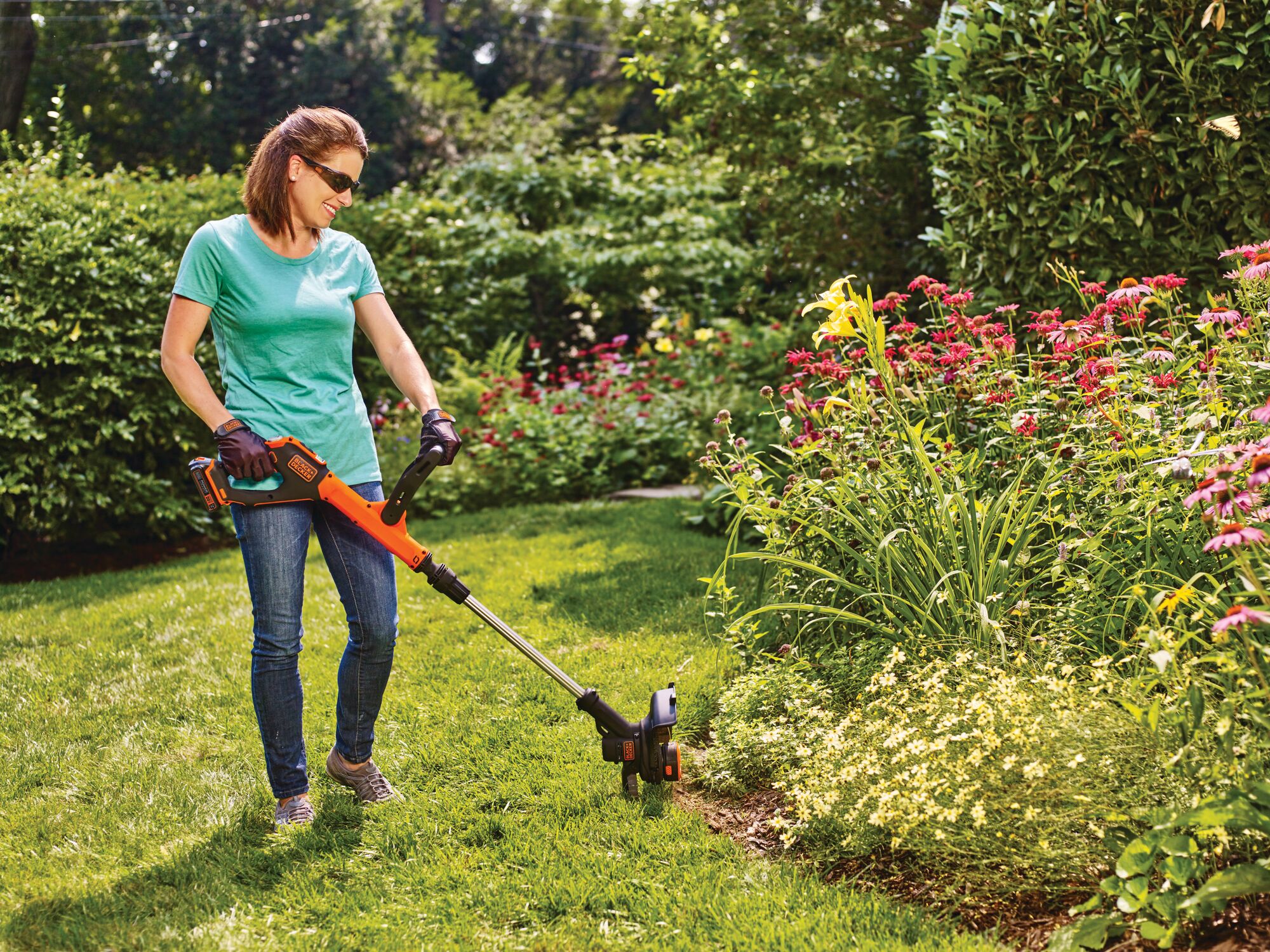 20 volt MAX Lithium EASYFEED String Trimmer / Edger 2 Lithium Ion Batteries being used by a person outside on grass.