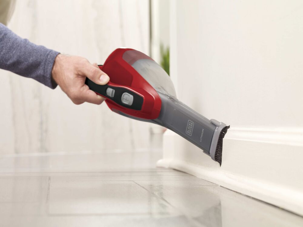 Dustbuster Advanced Clean Cordless Hand Vacuum with brush attachment being used to clean baseboard of wall.
