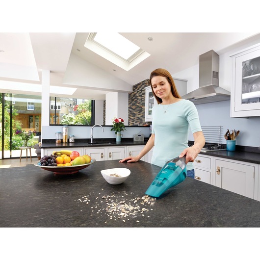 dustbuster QuickClean cordless hand vacuum wet dry being used by a person to clean food spillage on kitchen counter.