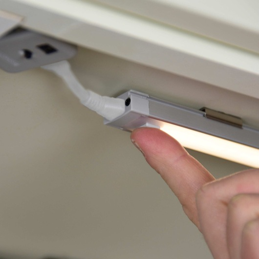 9 inch 1 bar LED under cabinet lighting being touched by a person.