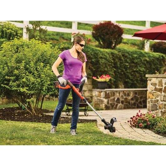 Lithium string trimmer being used by a person to Edge along sidewalks.