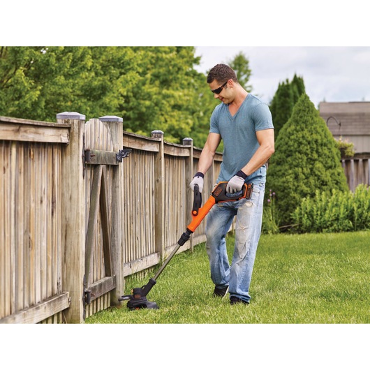 Lithium 12 inch 2 speed string trimmer / edger being used by a person to trim grass.
