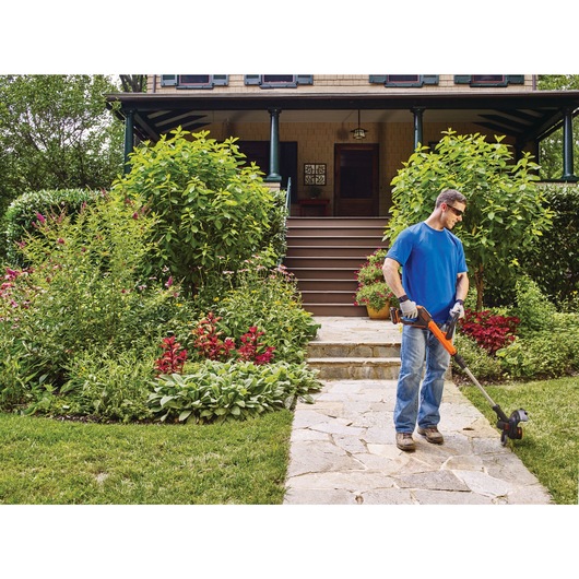 Lithium EASYFEED String Trimmer and Edger being used for trimming grass edges by person.