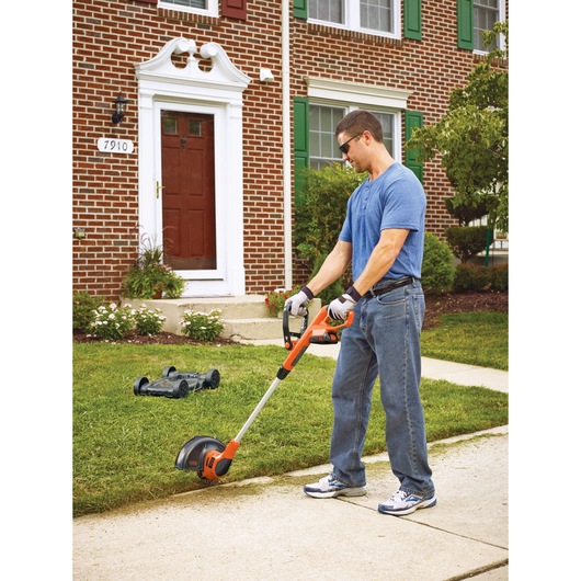 20 volt MAX lithium 12 inch 3 in 1 compact mower being used by a person to trim grass.