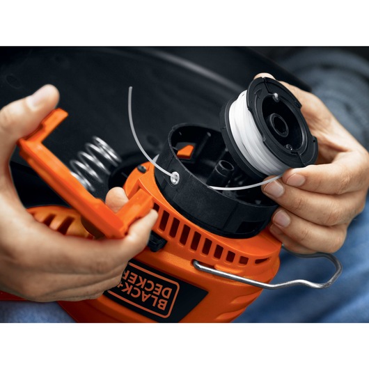 Person changing spool of 4 and 4 tenths Ampere 13 inch 2 in 1 Trimmer Edger.